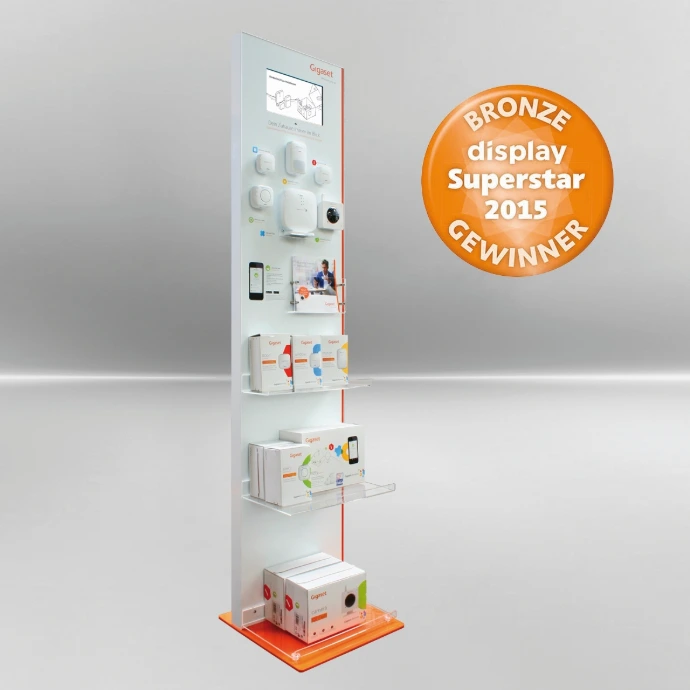 Ein Präsentationsdisplay in den Kundenfarbei Weiß/Orange, mit verschiedenen Produkten festmontiert oder eingepackt auf Ablageflächen. Am oberen Ende ist ein Bildschirm für Produktvideos eingelassen.